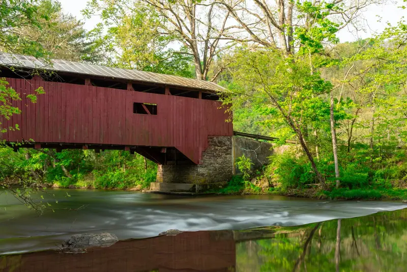 A red covered bridge over a creek in spring