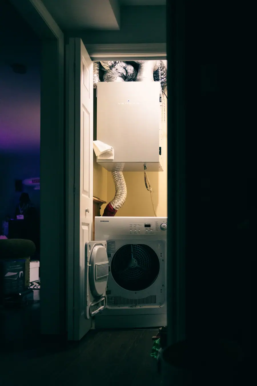 Stacked washer and dryer in a laundry closet with the dryer duct overhead