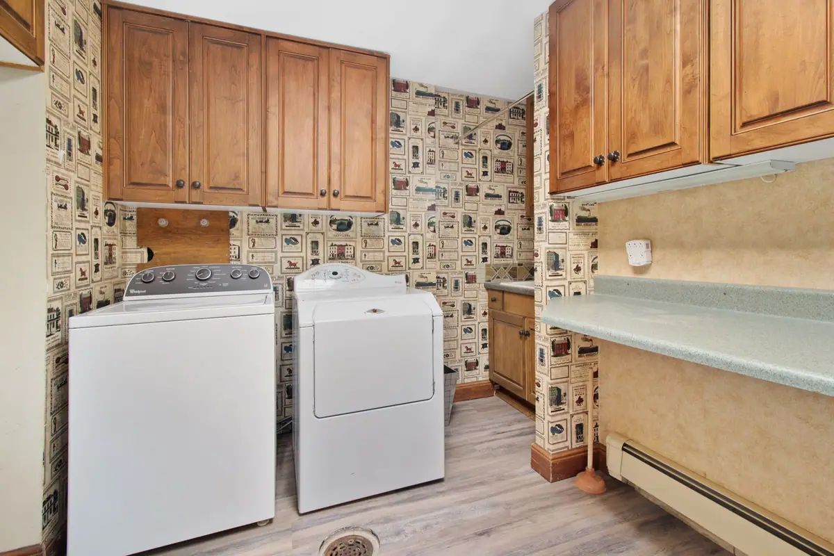 Home laundry room with a washer and dryer under wood cabinets