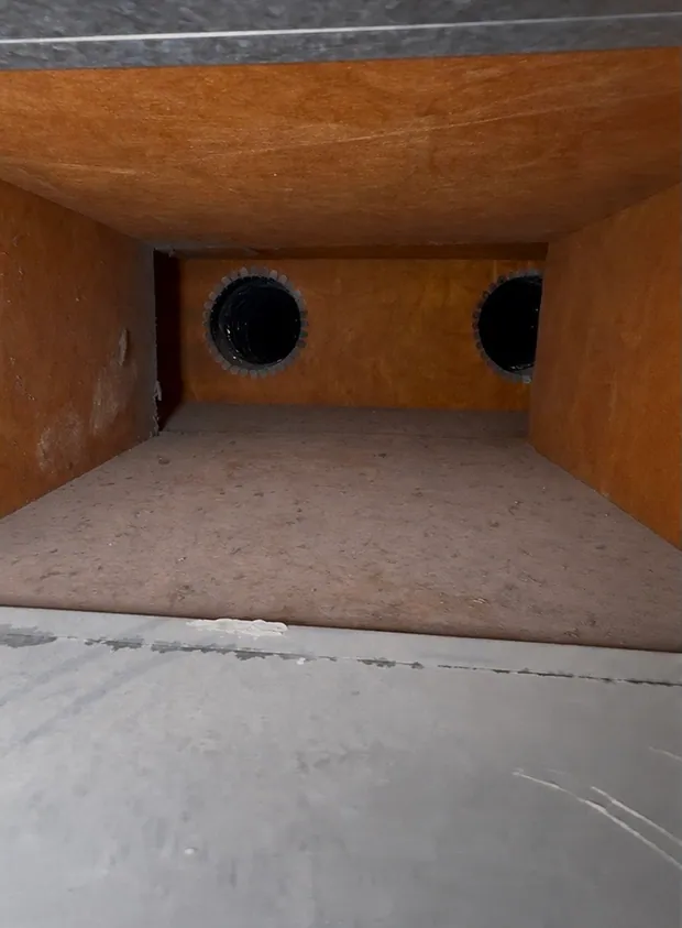The end of a trunk line and two branch takeoffs before cleaning, dust across the floor of the duct
